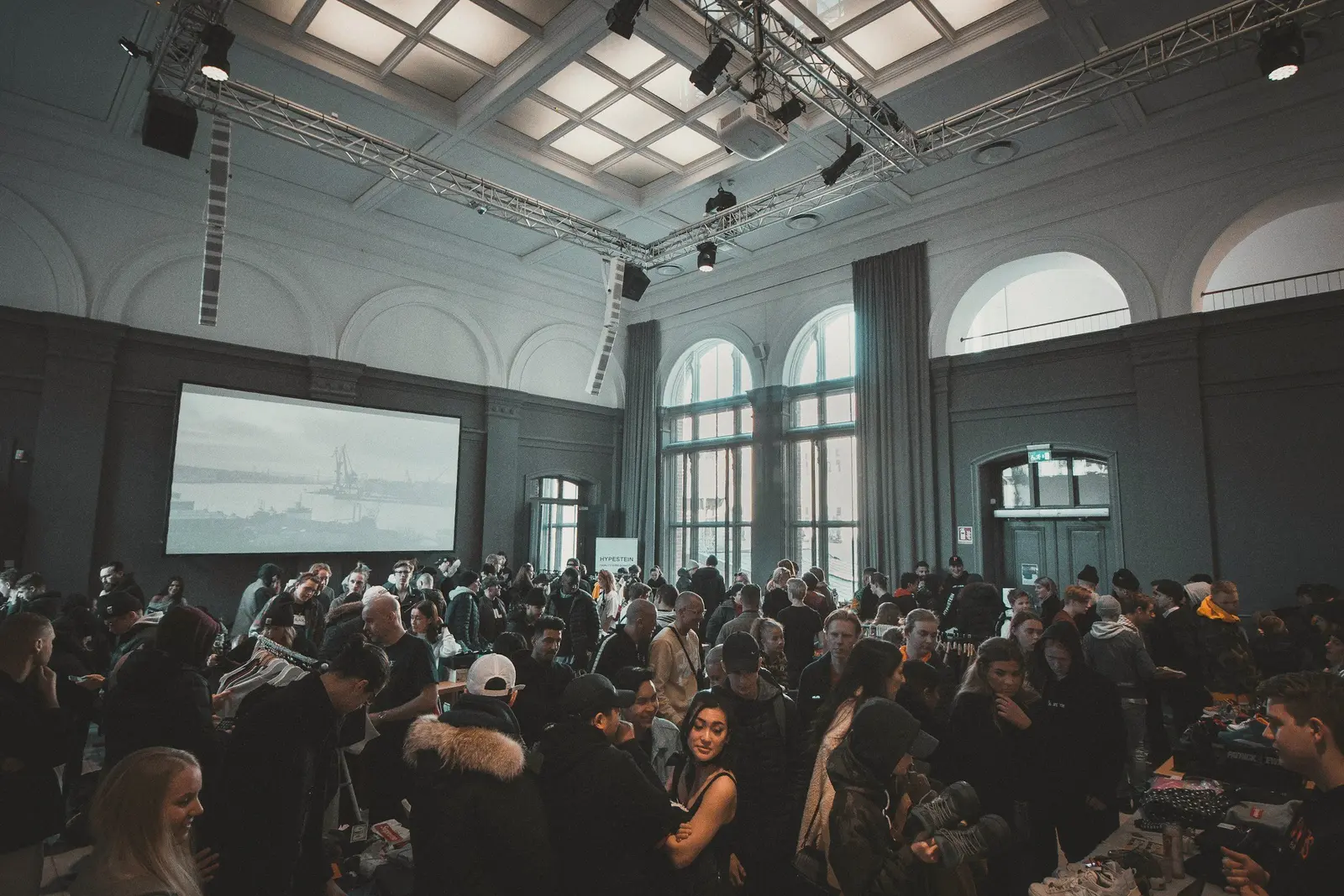 Audience watching a presentation in a high-ceilinged hall