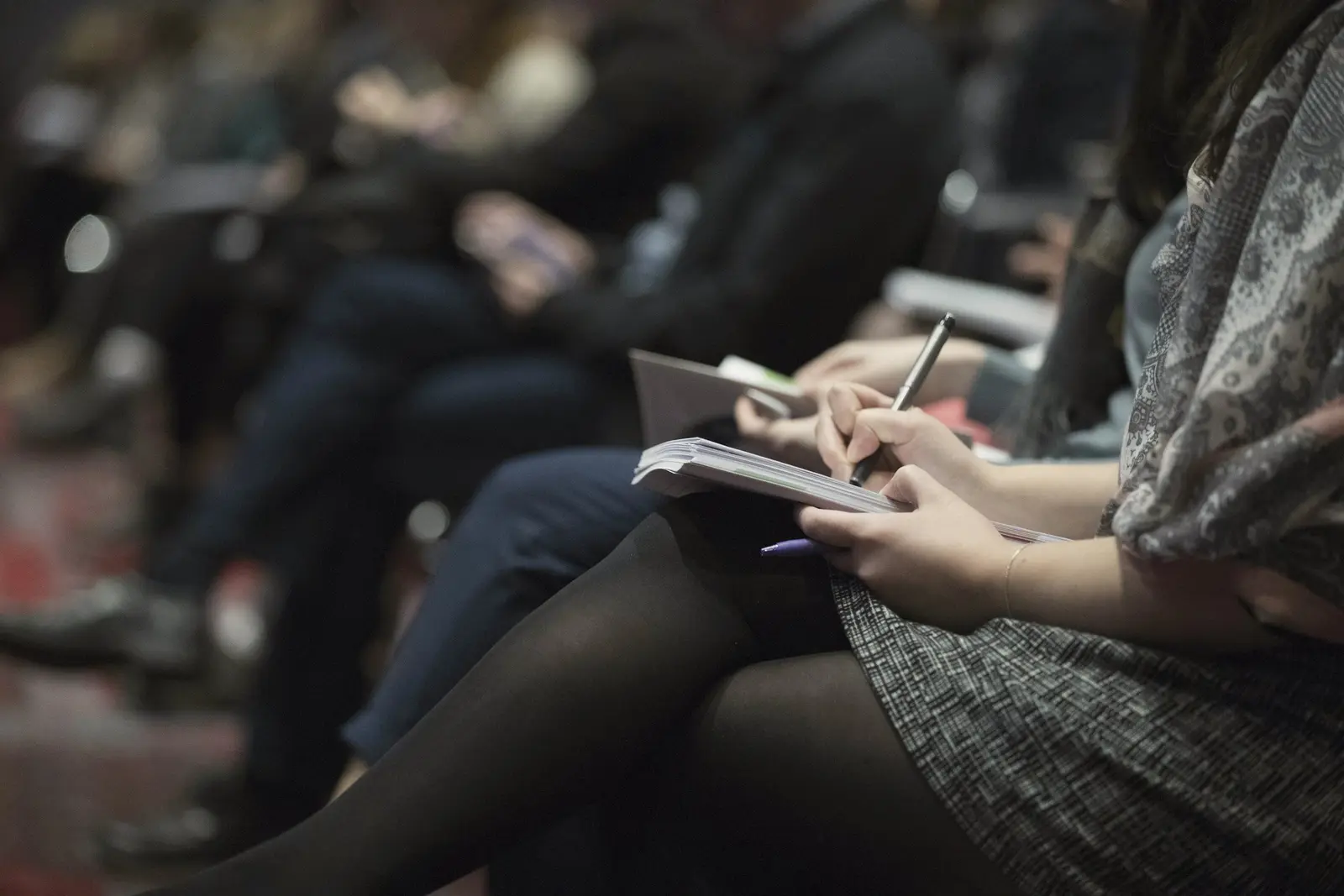 Attendee taking notes in a notebook during a talk