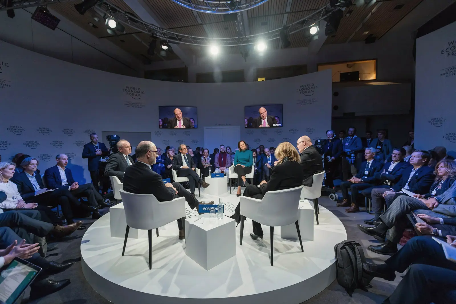 Panel discussion on a round stage with a large audience